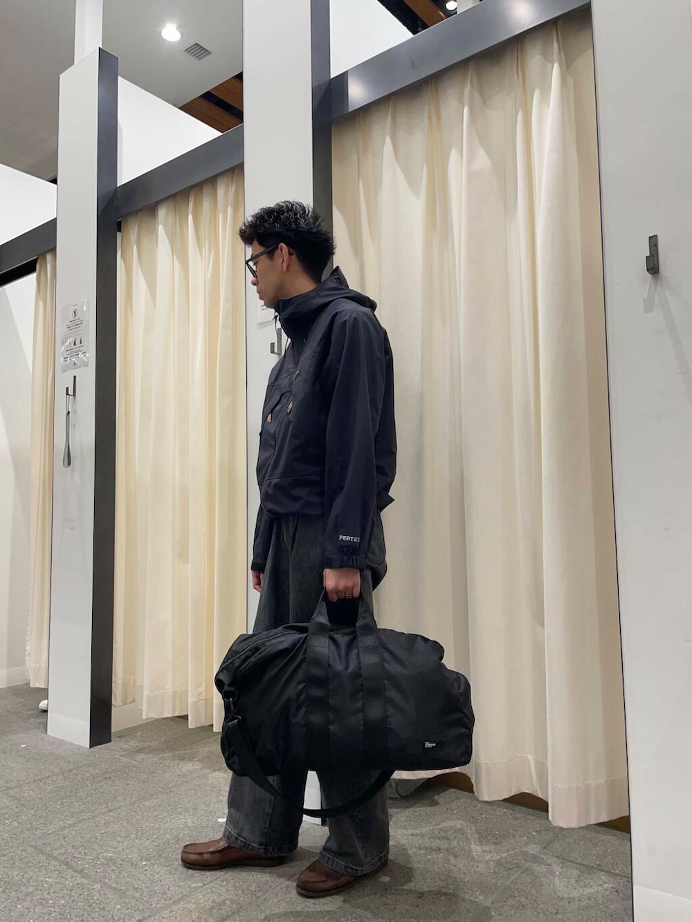 ブラウン系のローファー、ブラック系のデニムパンツ、ブラック系のボストンバッグを着用したメンズの春コーディネートの2枚目の写真