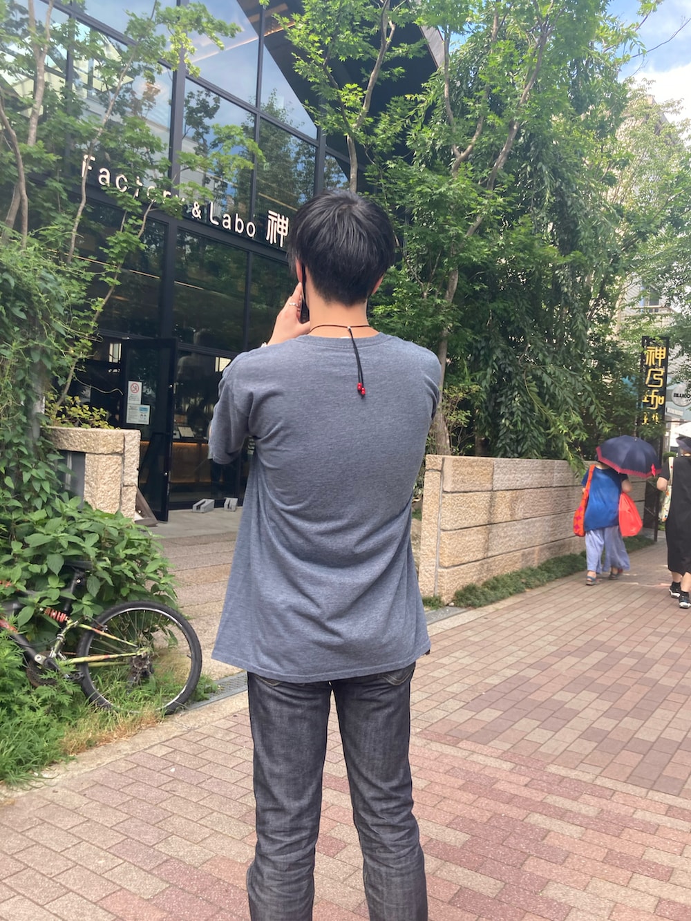 ブラック系のTシャツ/カットソー、ブルー系のデニムパンツ、ブラック系のスニーカーを着用したメンズの夏コーディネートの2枚目の写真