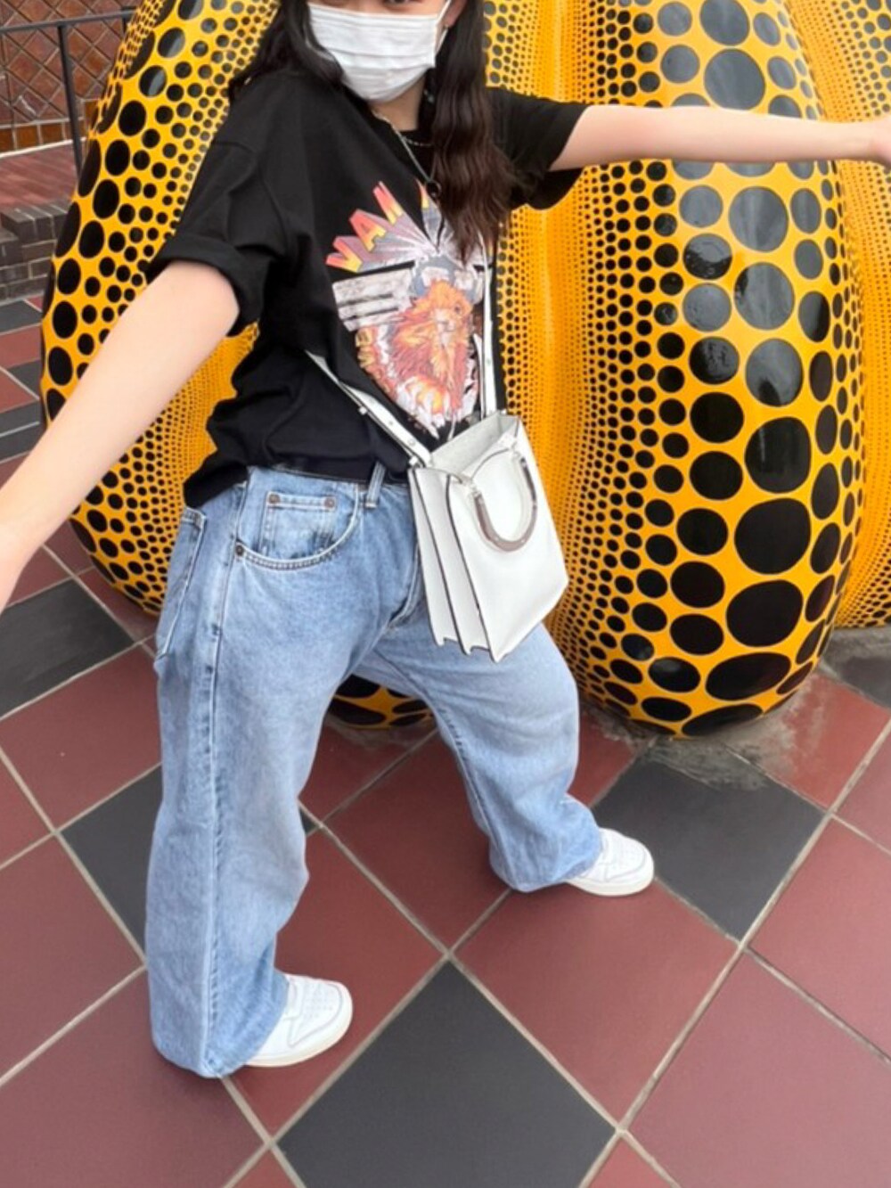 ホワイト系のショルダーバッグ、ホワイト系のスニーカー、ブルー系のデニムパンツを着用したレディースの夏コーディネートの2枚目の写真