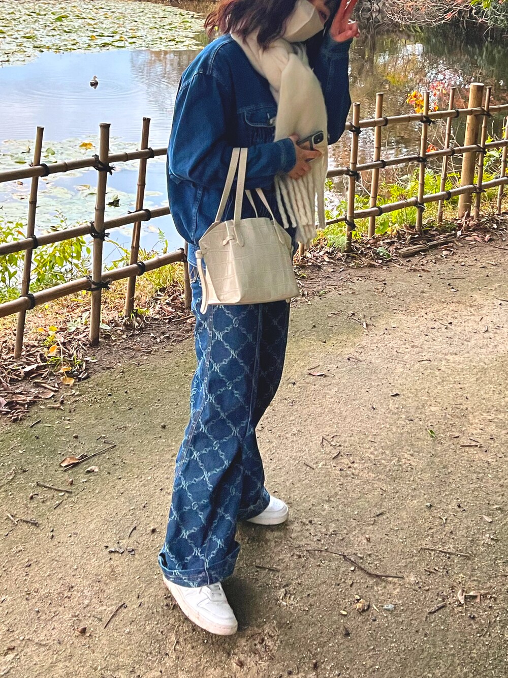 ホワイト系のバッグ、ブルー系のパンツ、ホワイト系のスニーカーを着用したレディースの冬コーディネートの2枚目の写真