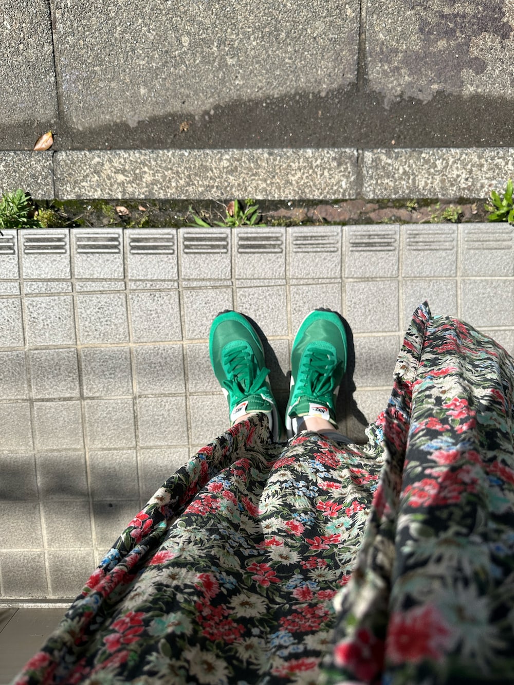 レッド系のワンピース、ブルー系のデニムパンツ、グリーン系のスニーカーを着用したレディースの夏コーディネートの2枚目の写真