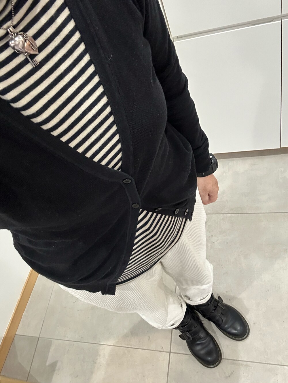 ベージュ系のTシャツ/カットソー、ブラック系のカーディガン/ボレロ、ホワイト系のその他パンツを着用したレディースの冬コーディネートの2枚目の写真