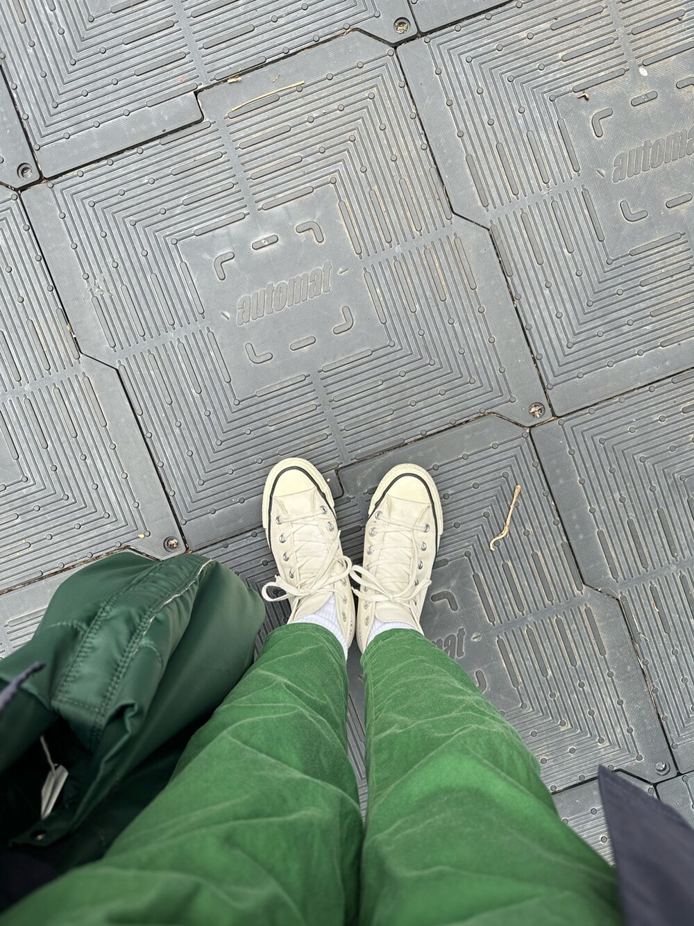 グリーン系のTシャツ/カットソー、グリーン系のチノパンツ、ブルー系のステンカラーコートを着用したレディースの春コーディネートの2枚目の写真