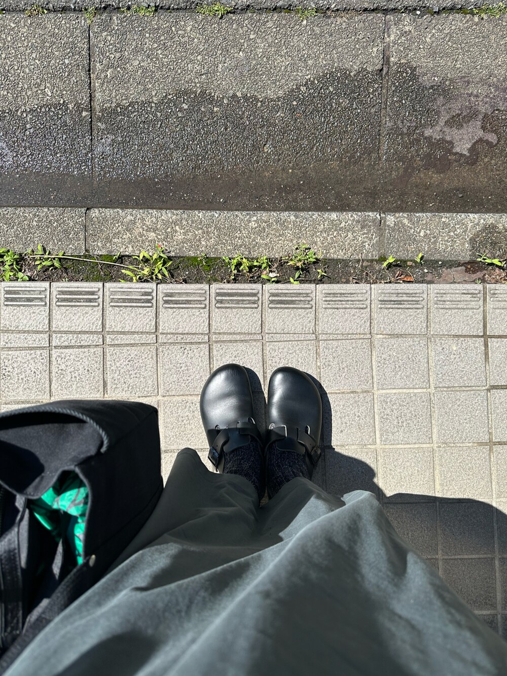 グレー系のワンピース、ブラック系のカーディガン/ボレロ、ブラック系のサンダルを着用したレディースの春コーディネートの2枚目の写真