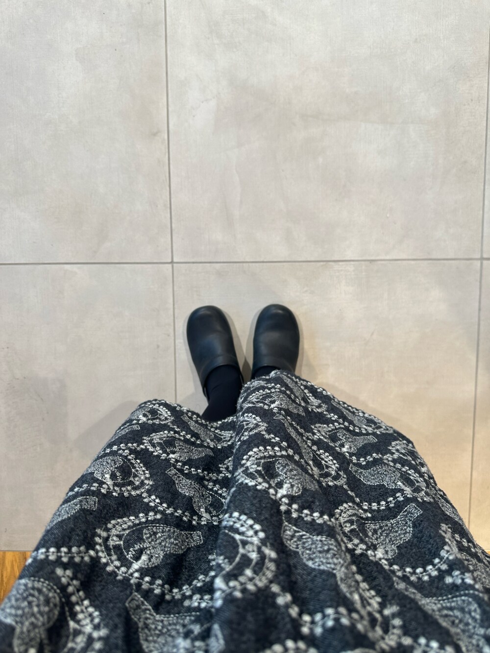 グレー系のTシャツ/カットソー、ブラック系のカーディガン/ボレロ、グレー系のスカートを着用したレディースの秋コーディネートの2枚目の写真