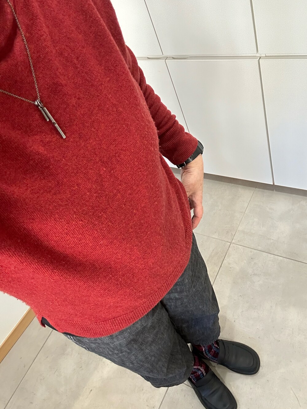 レッド系のニット/セーター、グレー系のピーコート、ブラック系のデニムパンツを着用したレディースの冬コーディネートの2枚目の写真