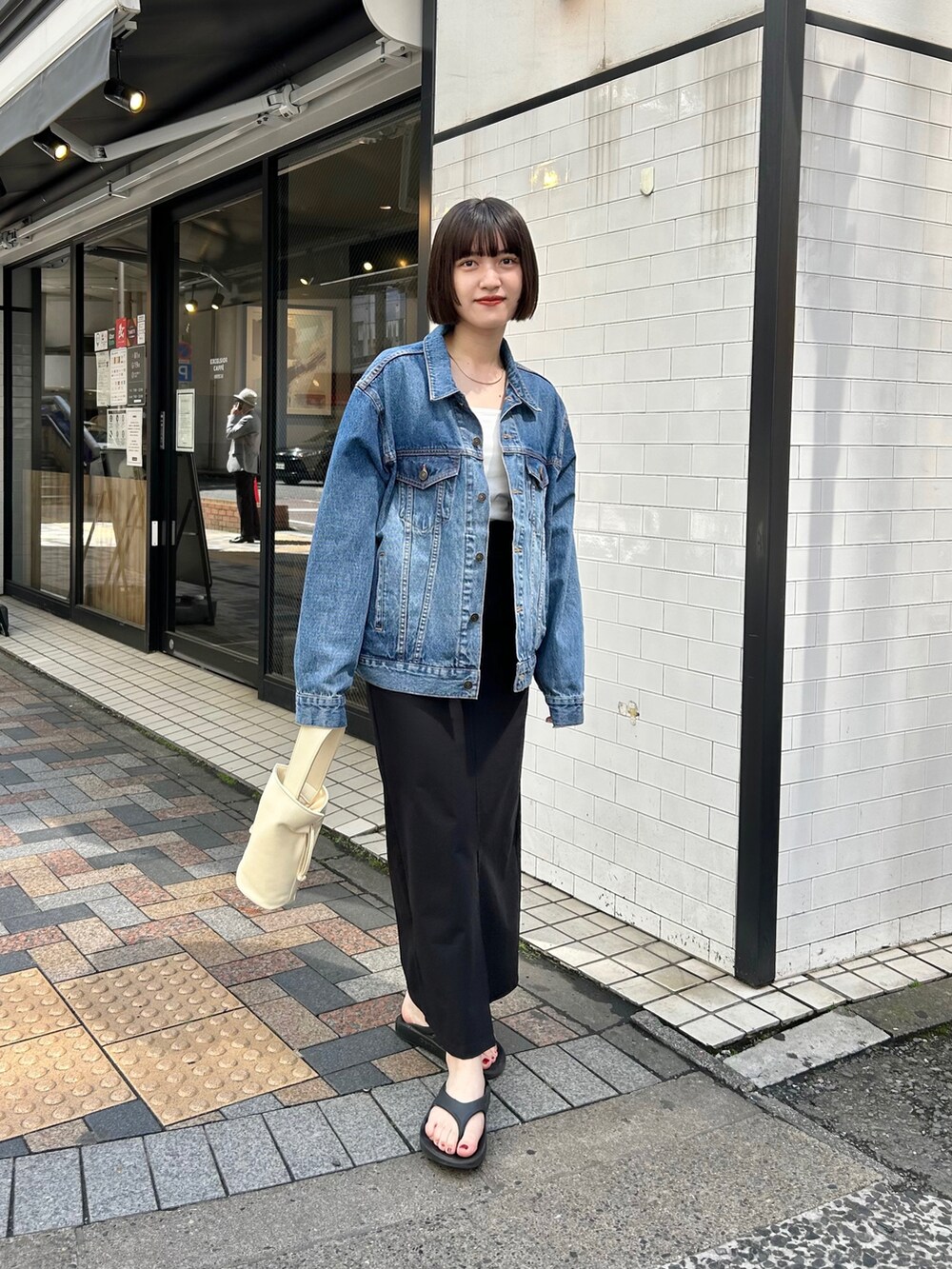 ブルー系のデニムジャケット、ブラック系のスカート、ホワイト系のハンドバッグを着用したレディースの春コーディネートの2枚目の写真