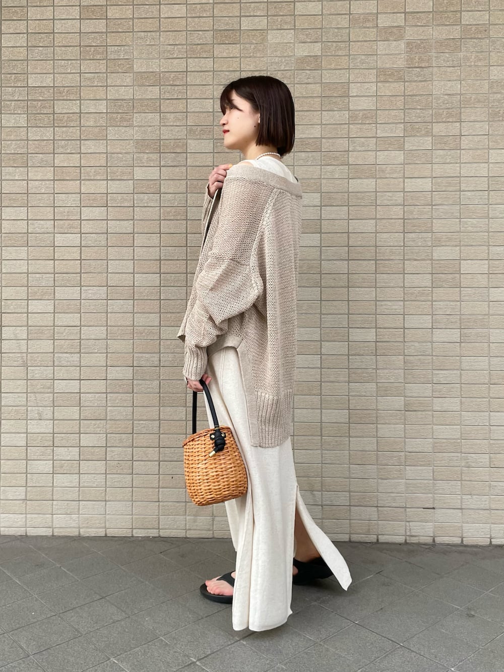 ベージュ系のワンピース、ベージュ系のカーディガン/ボレロ、ブラック系のサンダルを着用したレディースの春コーディネートの2枚目の写真