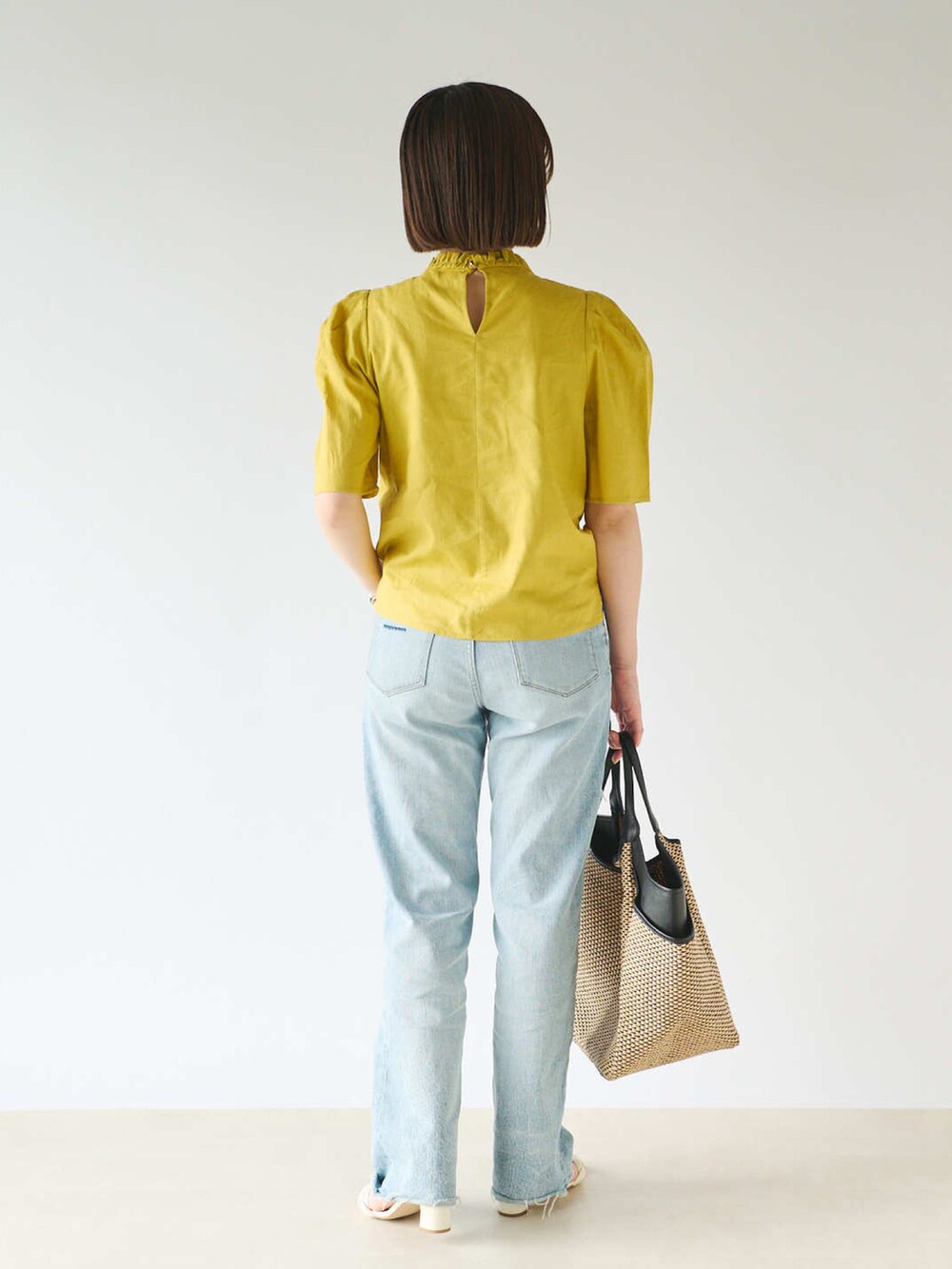 イエロー系のシャツ/ブラウス、ブルー系のデニムパンツ、ブラック系のかごバッグを着用したレディースの春コーディネートの3枚目の写真