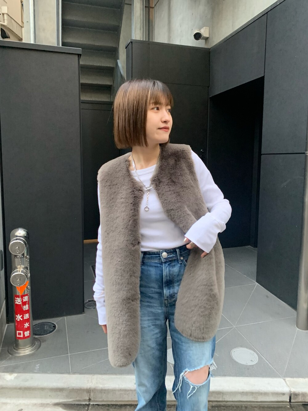 ブラウン系のベスト、ホワイト系のTシャツ/カットソー、ブラック系のブーツを着用したレディースの冬コーディネートの2枚目の写真