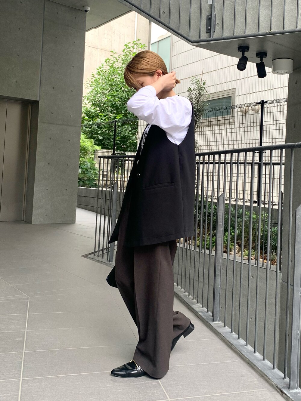 ブラック系のベスト、ホワイト系のTシャツ/カットソー、ブラック系のハンドバッグを着用したレディースの秋コーディネートの2枚目の写真