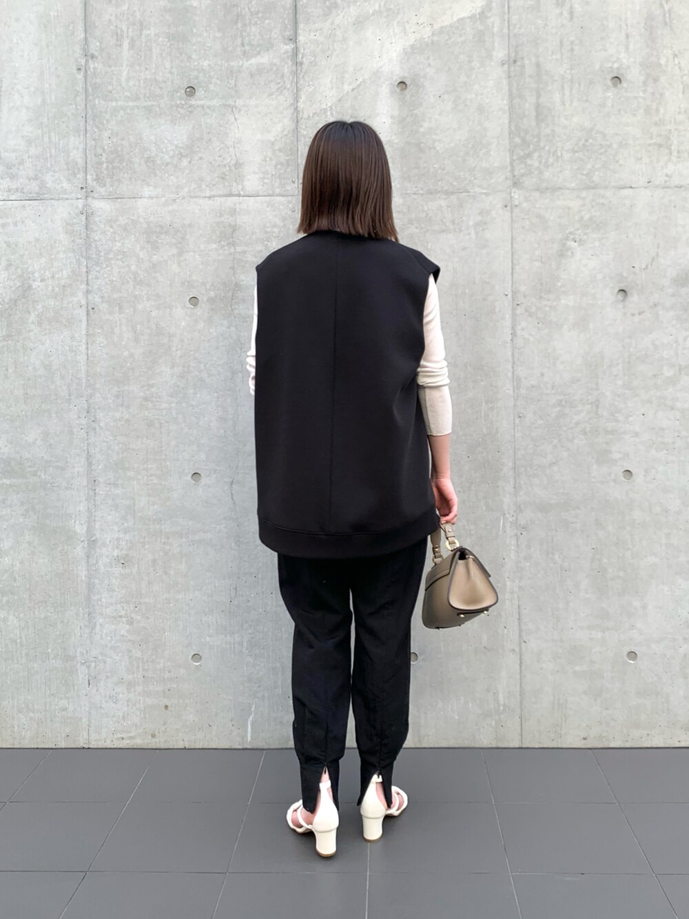 ブラック系のベスト、ホワイト系のTシャツ/カットソー、グレー系のショルダーバッグを着用したレディースの冬コーディネートの3枚目の写真