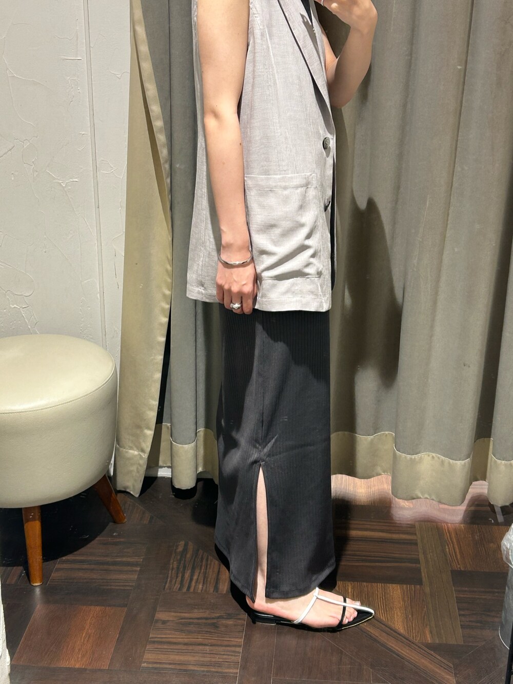 グレー系のベスト、グレー系のワンピース、シルバー系のネックレスを着用したレディースの夏コーディネートの6枚目の写真