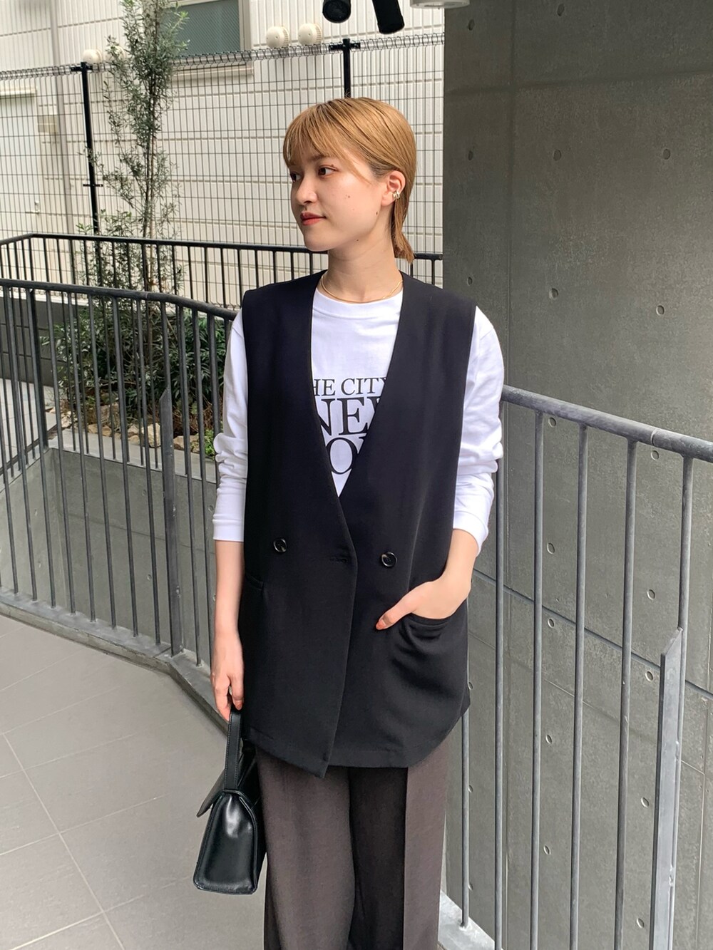 ブラック系のベスト、ホワイト系のTシャツ/カットソー、ブラック系のハンドバッグを着用したレディースの秋コーディネートの3枚目の写真