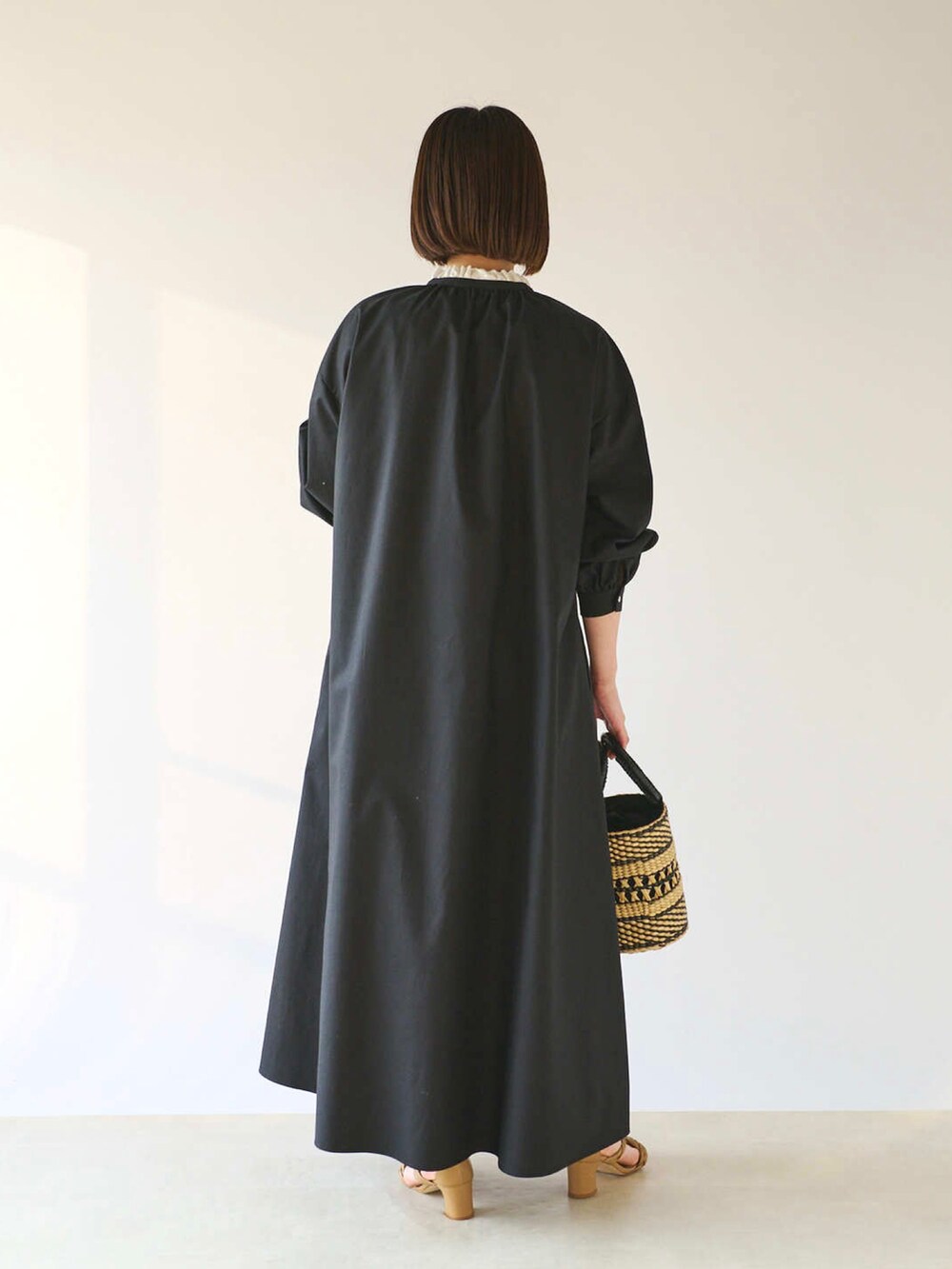 ブラック系のワンピース、ベージュ系のかごバッグ、ベージュ系のサンダルを着用したレディースの春コーディネートの4枚目の写真