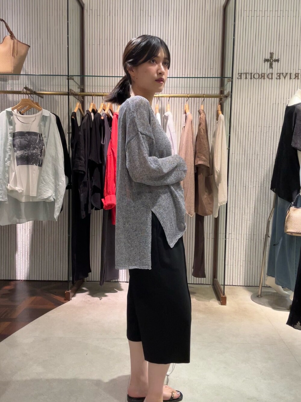 グレー系のニット/セーター、ブラック系のその他パンツ、シルバー系のネックレスを着用したレディースの夏コーディネートの4枚目の写真