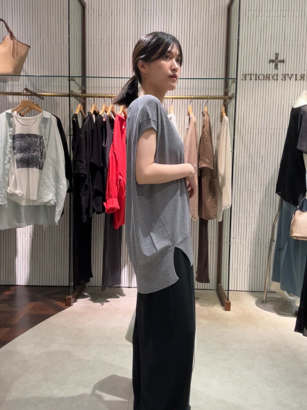 グレー系のニット/セーター、ブラック系のスラックス、ホワイト系のボディバッグ/ウエストポーチを着用したレディースの夏コーディネートの4枚目の写真