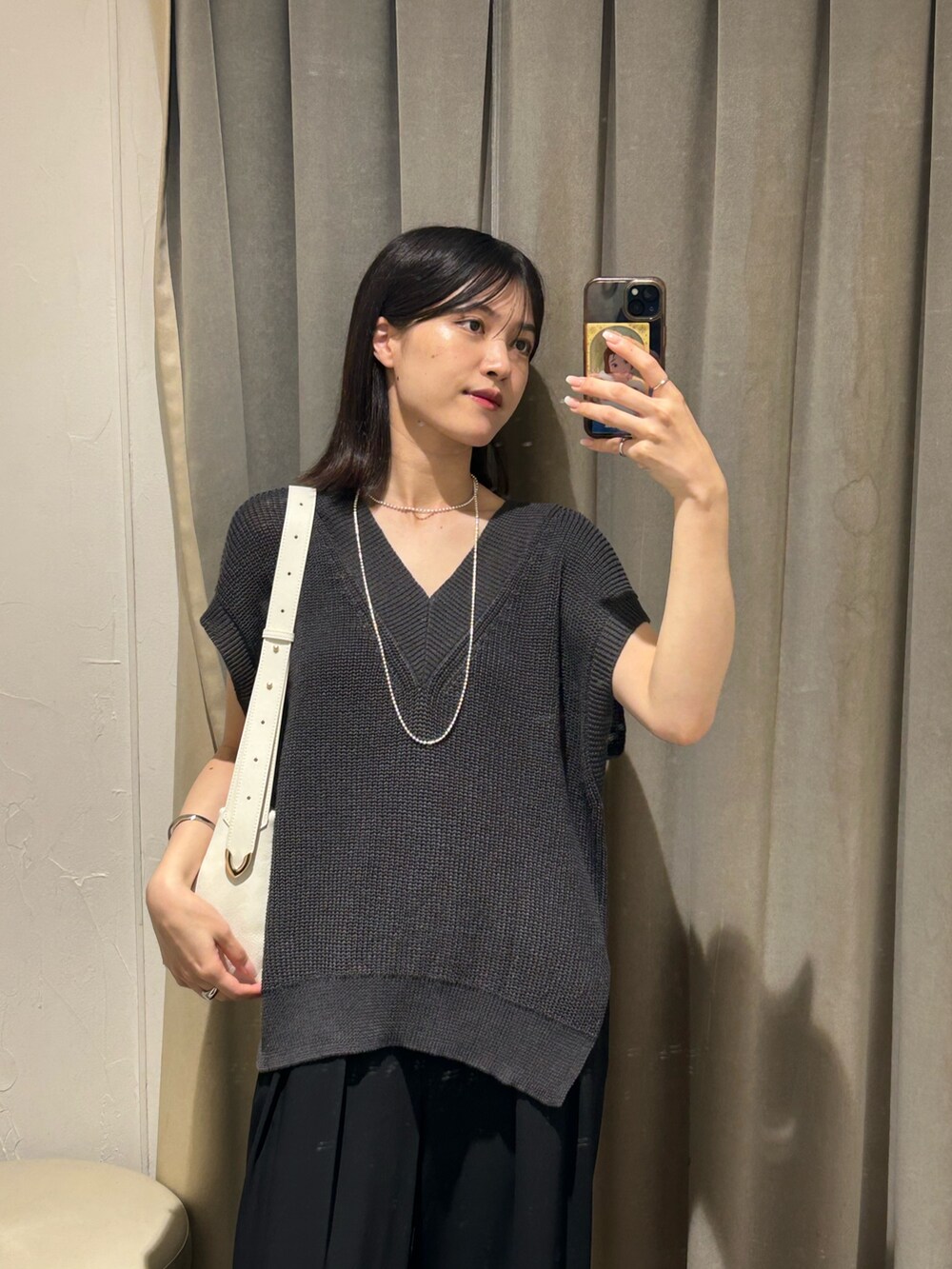 グレー系のニット/セーター、ブラック系のスラックス、ホワイト系のボディバッグ/ウエストポーチを着用したレディースの夏コーディネートの3枚目の写真