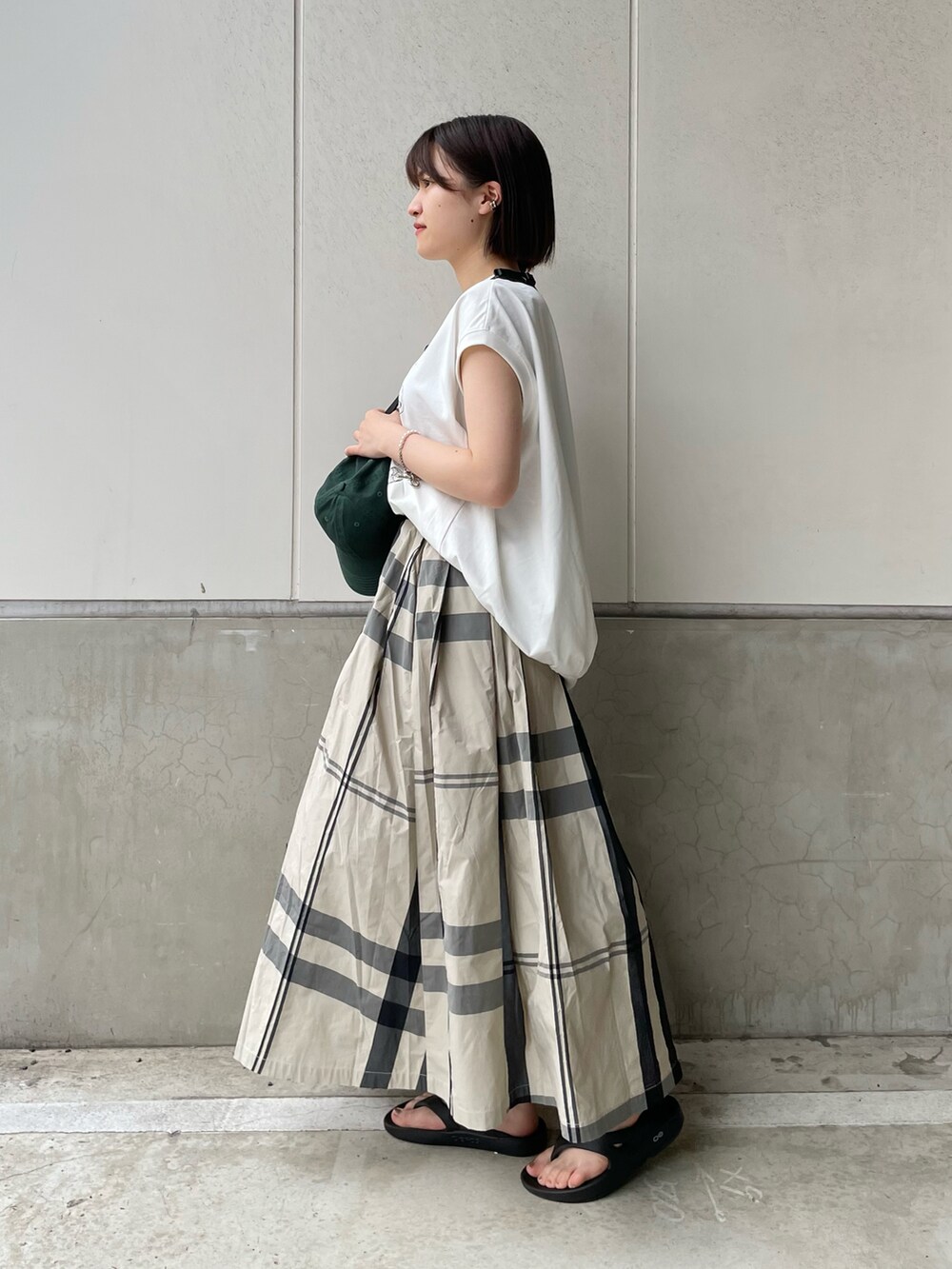 ブラック系のボディバッグ/ウエストポーチ、ホワイト系のスカート、ブラック系のサンダルを着用したレディースの春コーディネートの2枚目の写真