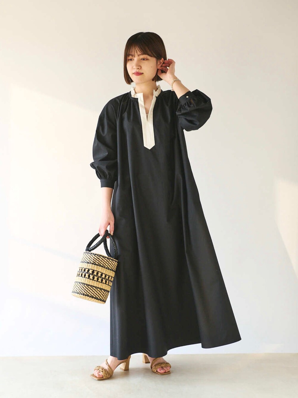 ブラック系のワンピース、ベージュ系のかごバッグ、ベージュ系のサンダルを着用したレディースの春コーディネートの2枚目の写真