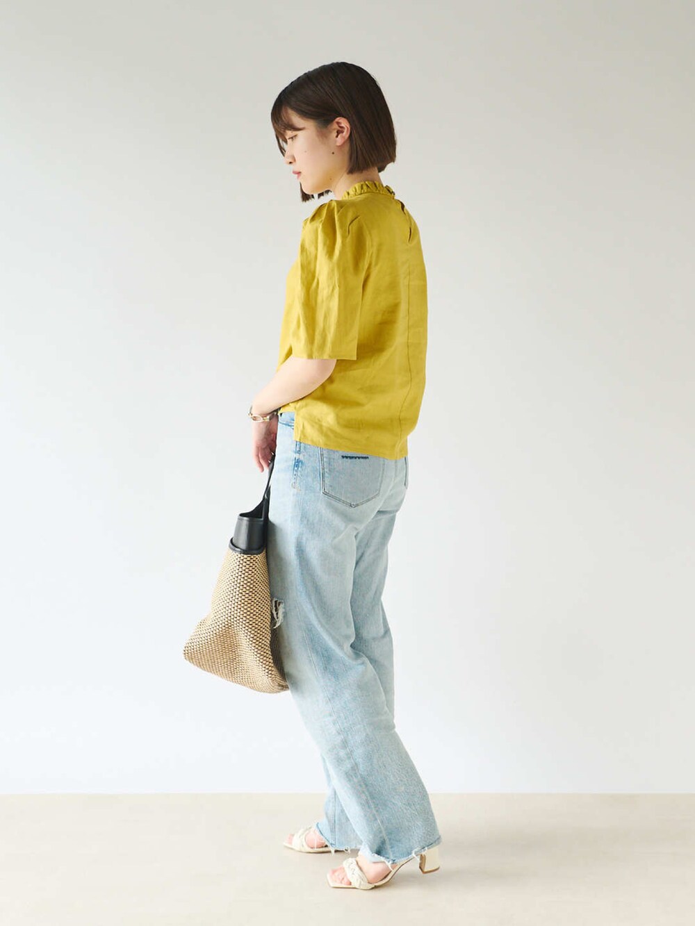 イエロー系のシャツ/ブラウス、ブルー系のデニムパンツ、ブラック系のかごバッグを着用したレディースの春コーディネートの2枚目の写真