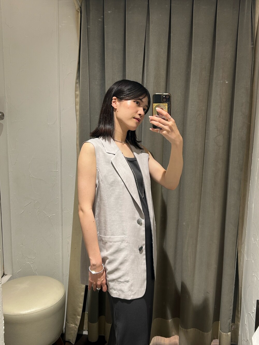 グレー系のベスト、グレー系のワンピース、シルバー系のネックレスを着用したレディースの夏コーディネートの4枚目の写真