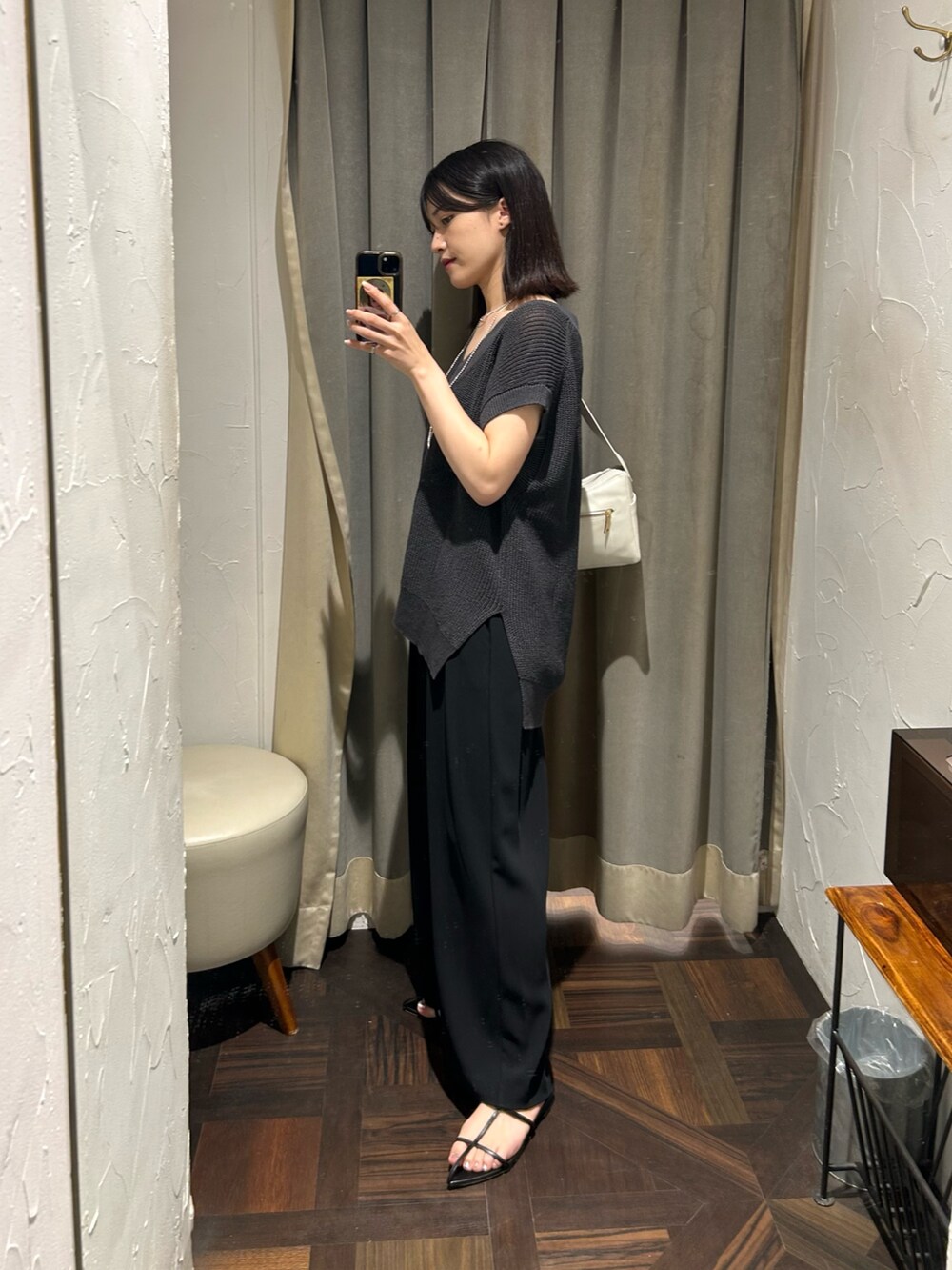 グレー系のニット/セーター、ブラック系のスラックス、ホワイト系のボディバッグ/ウエストポーチを着用したレディースの夏コーディネートの2枚目の写真