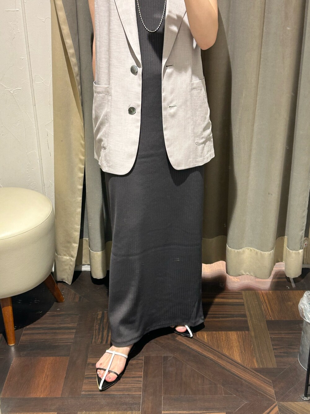 グレー系のベスト、グレー系のワンピース、シルバー系のネックレスを着用したレディースの夏コーディネートの5枚目の写真