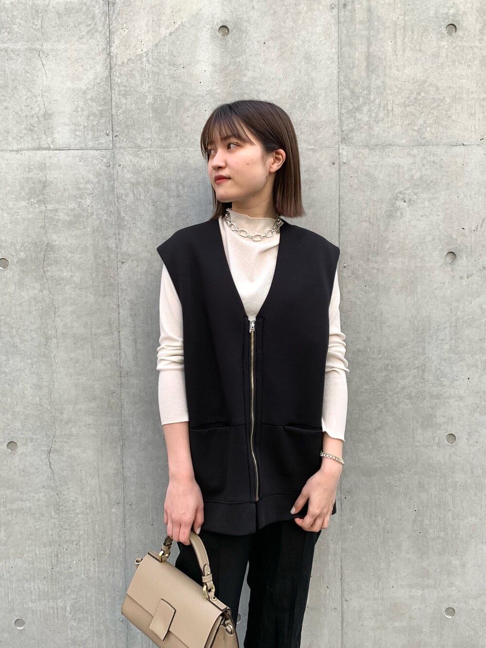 ブラック系のベスト、ホワイト系のTシャツ/カットソー、グレー系のショルダーバッグを着用したレディースの冬コーディネートの4枚目の写真