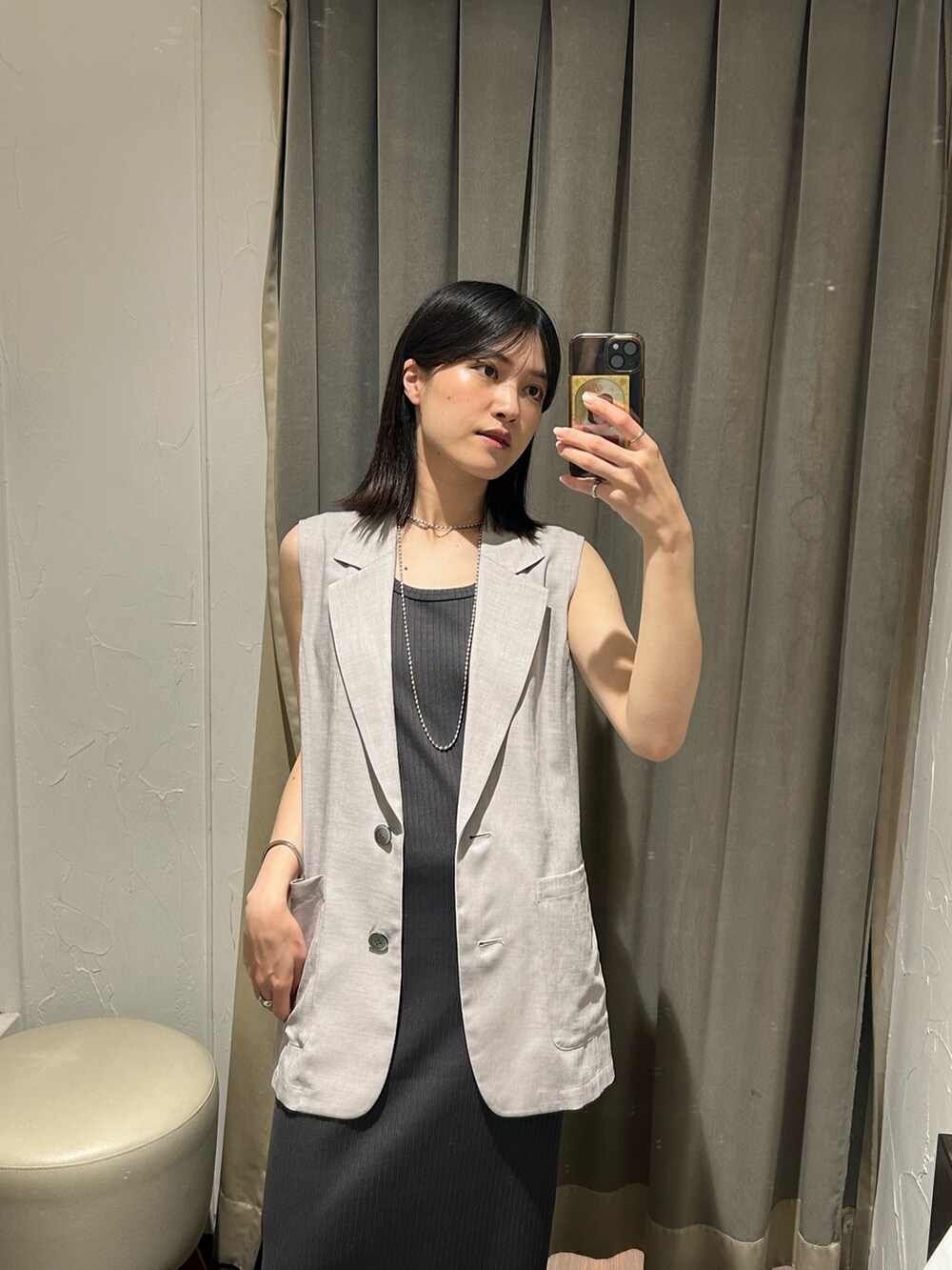 グレー系のベスト、グレー系のワンピース、シルバー系のネックレスを着用したレディースの夏コーディネートの3枚目の写真