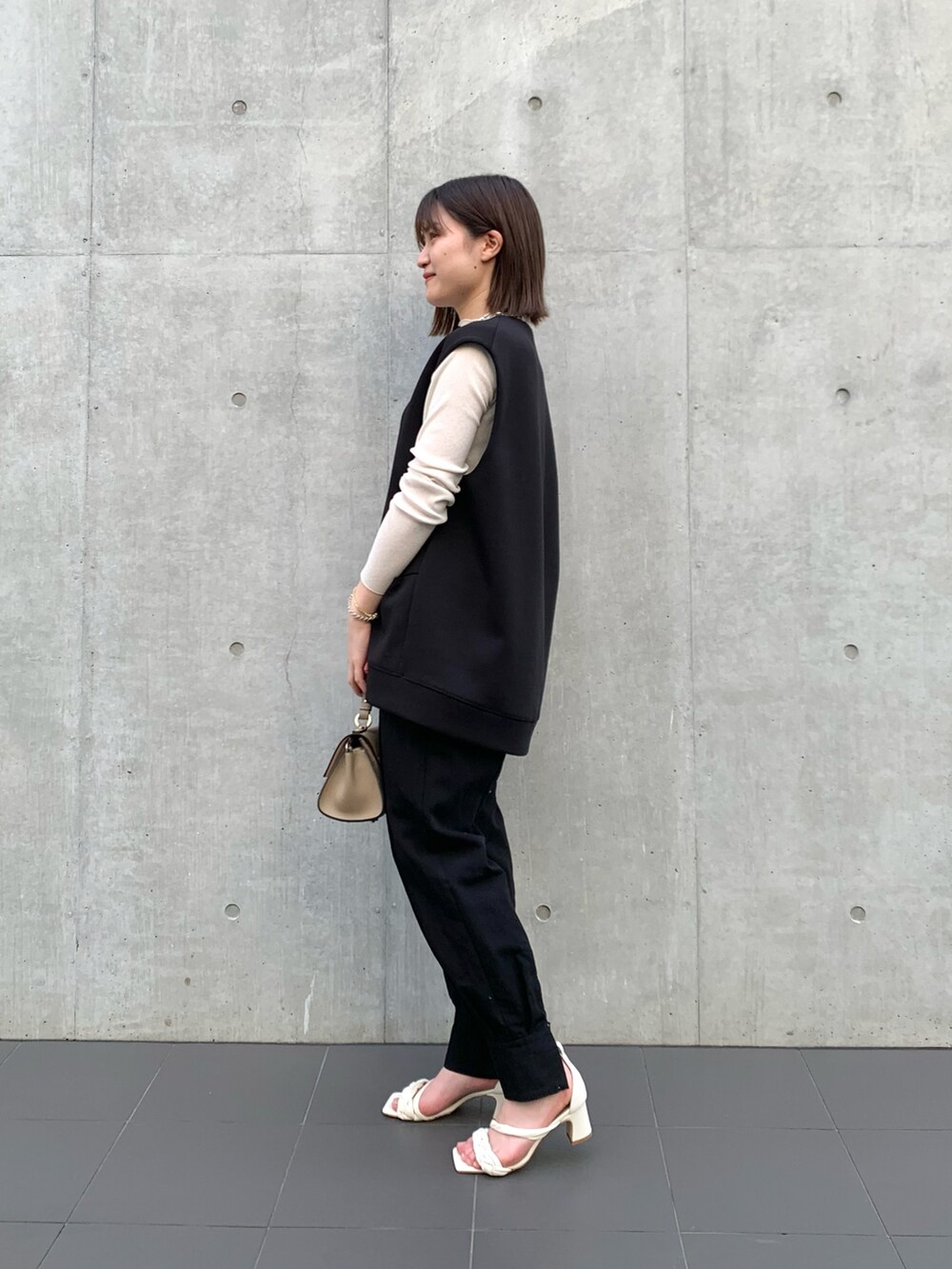 ブラック系のベスト、ホワイト系のTシャツ/カットソー、グレー系のショルダーバッグを着用したレディースの冬コーディネートの2枚目の写真