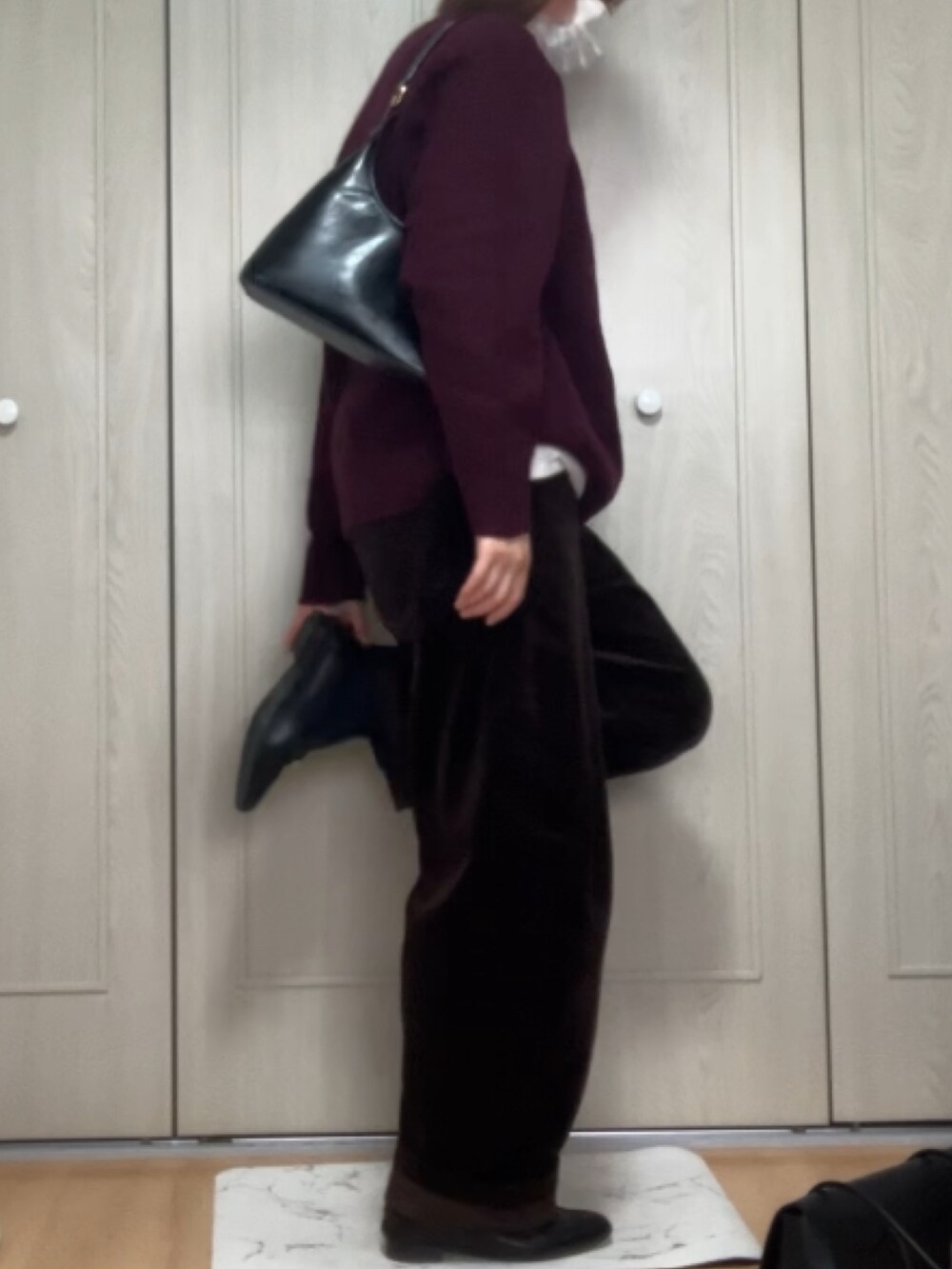 ブラック系のハンドバッグ、レッド系のニット/セーター、ブラウン系のパンツを着用したレディースの冬コーディネートの2枚目の写真