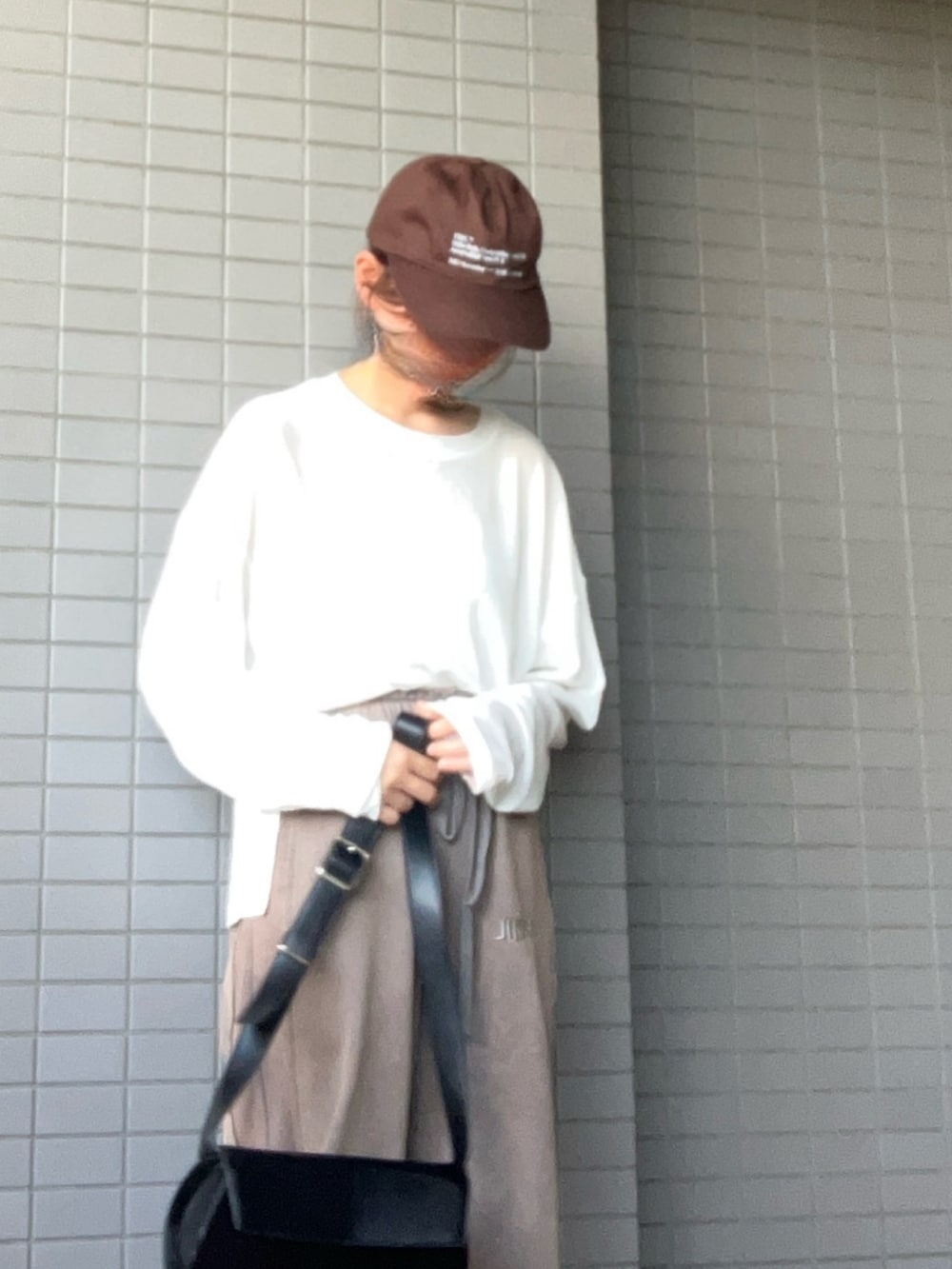 ブラック系のショルダーバッグ、ホワイト系のTシャツ/カットソー、グレー系のスウェットパンツを着用したレディースの秋コーディネートの2枚目の写真