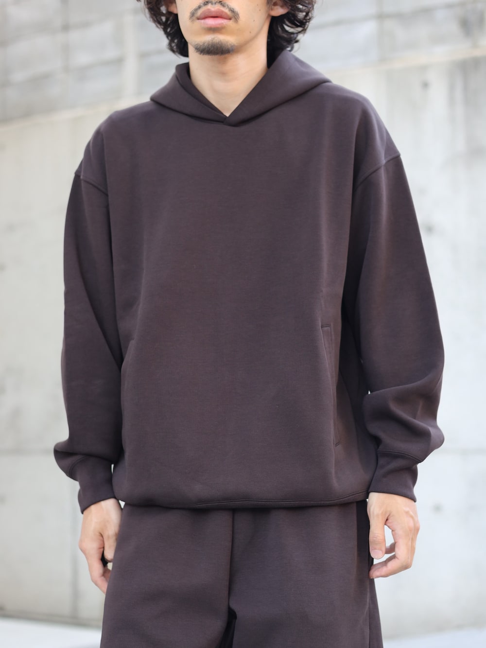 ブラック系のスニーカー、ブラウン系のスウェットパンツ、ブラウン系のパーカーを着用したメンズの秋コーディネートの2枚目の写真