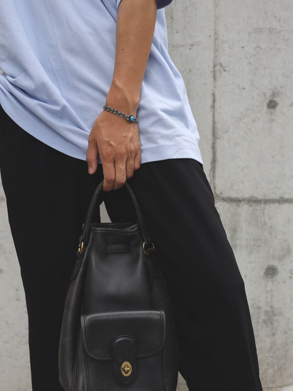 ブルー系のポロシャツ、ブラック系のショルダーバッグ、ホワイト系のスニーカーを着用したメンズの夏コーディネートの4枚目の写真