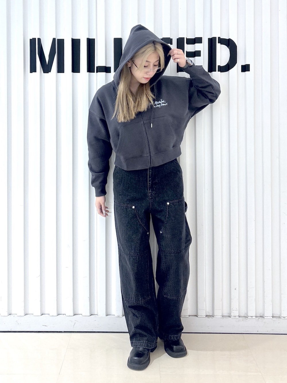 グレー系のパーカー、ブラック系のデニムパンツ、ブラック系のショルダーバッグを着用したレディースの冬コーディネートの5枚目の写真