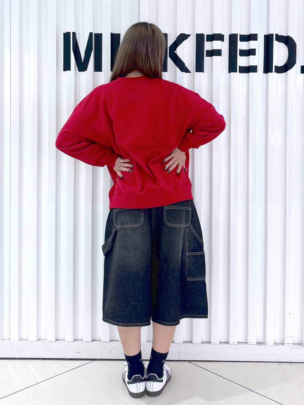 レッド系のスウェット、ホワイト系のデニムパンツ、レッド系のバックパック/リュックを着用したレディースの秋コーディネートの5枚目の写真