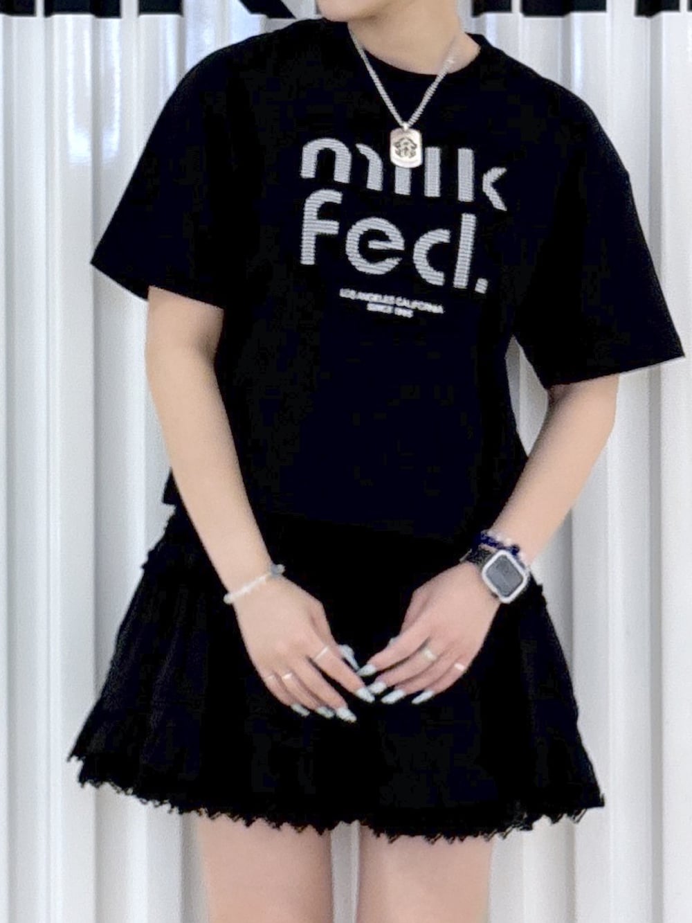ブラック系のTシャツ/カットソー、ブラック系のスカート、ホワイト系のショルダーバッグを着用したレディースの春コーディネートの5枚目の写真