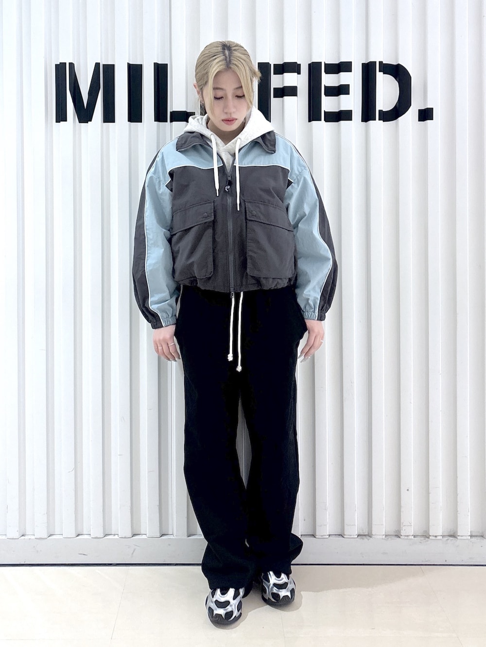 グレー系のナイロンジャケット、ベージュ系のパーカー、ブラック系のスウェットパンツを着用したレディースの春コーディネートの4枚目の写真