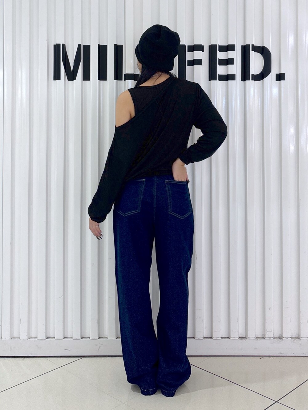ブルー系のデニムパンツ、ブラック系のTシャツ/カットソー、ブラック系のニットキャップ/ビーニーを着用したレディースの秋コーディネートの2枚目の写真