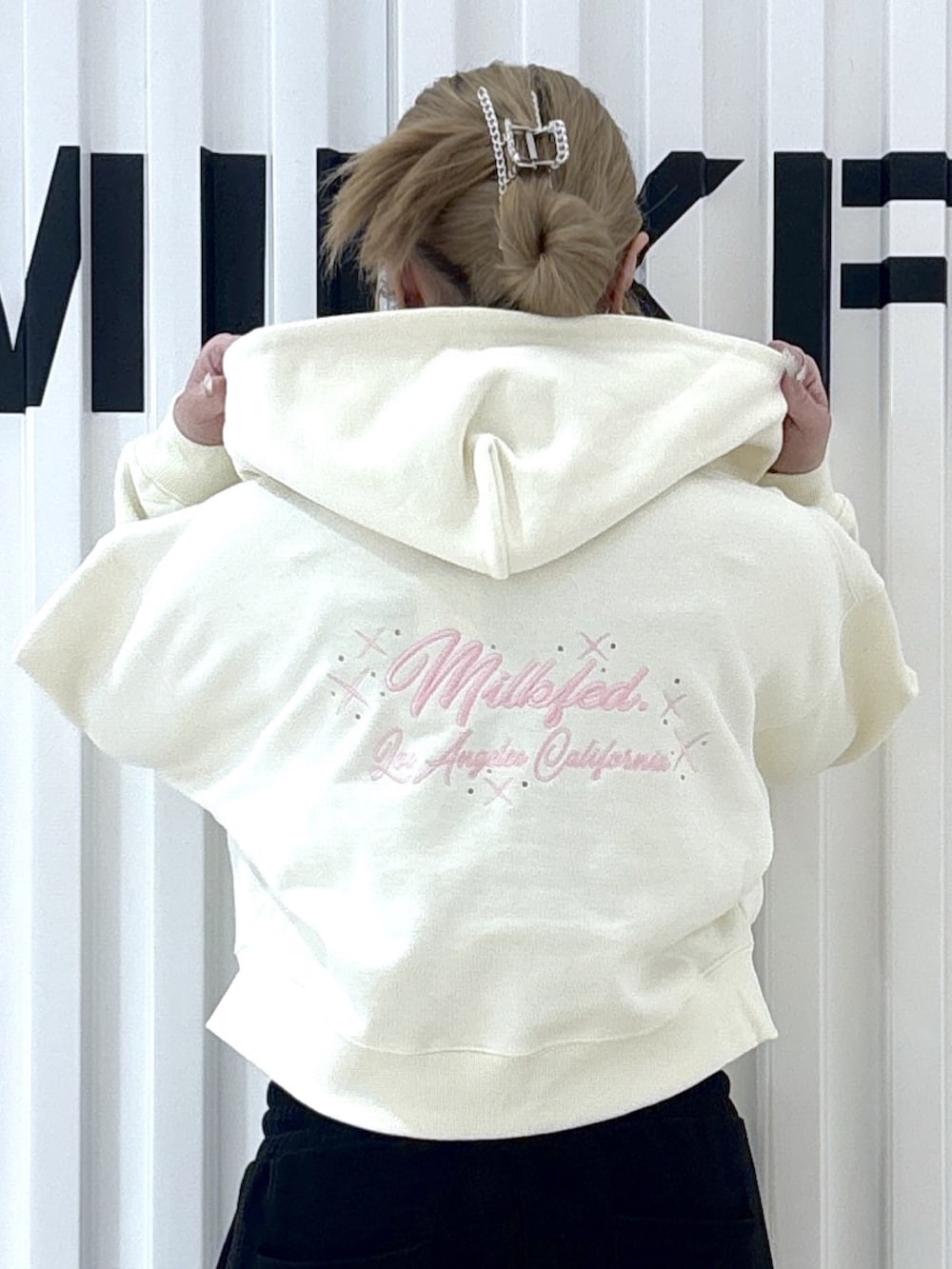 ホワイト系のパーカー、ブラック系のスウェットパンツを着用したレディースの春コーディネートの4枚目の写真