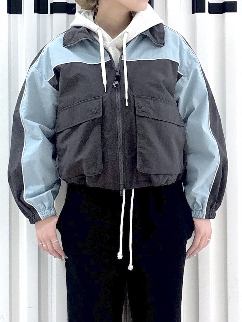 グレー系のナイロンジャケット、ベージュ系のパーカー、ブラック系のスウェットパンツを着用したレディースの春コーディネートの6枚目の写真