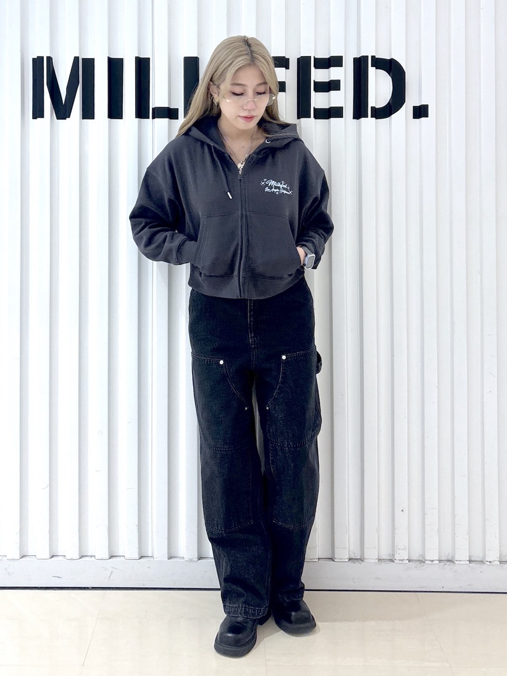 グレー系のパーカー、ブラック系のデニムパンツ、ブラック系のショルダーバッグを着用したレディースの冬コーディネートの3枚目の写真