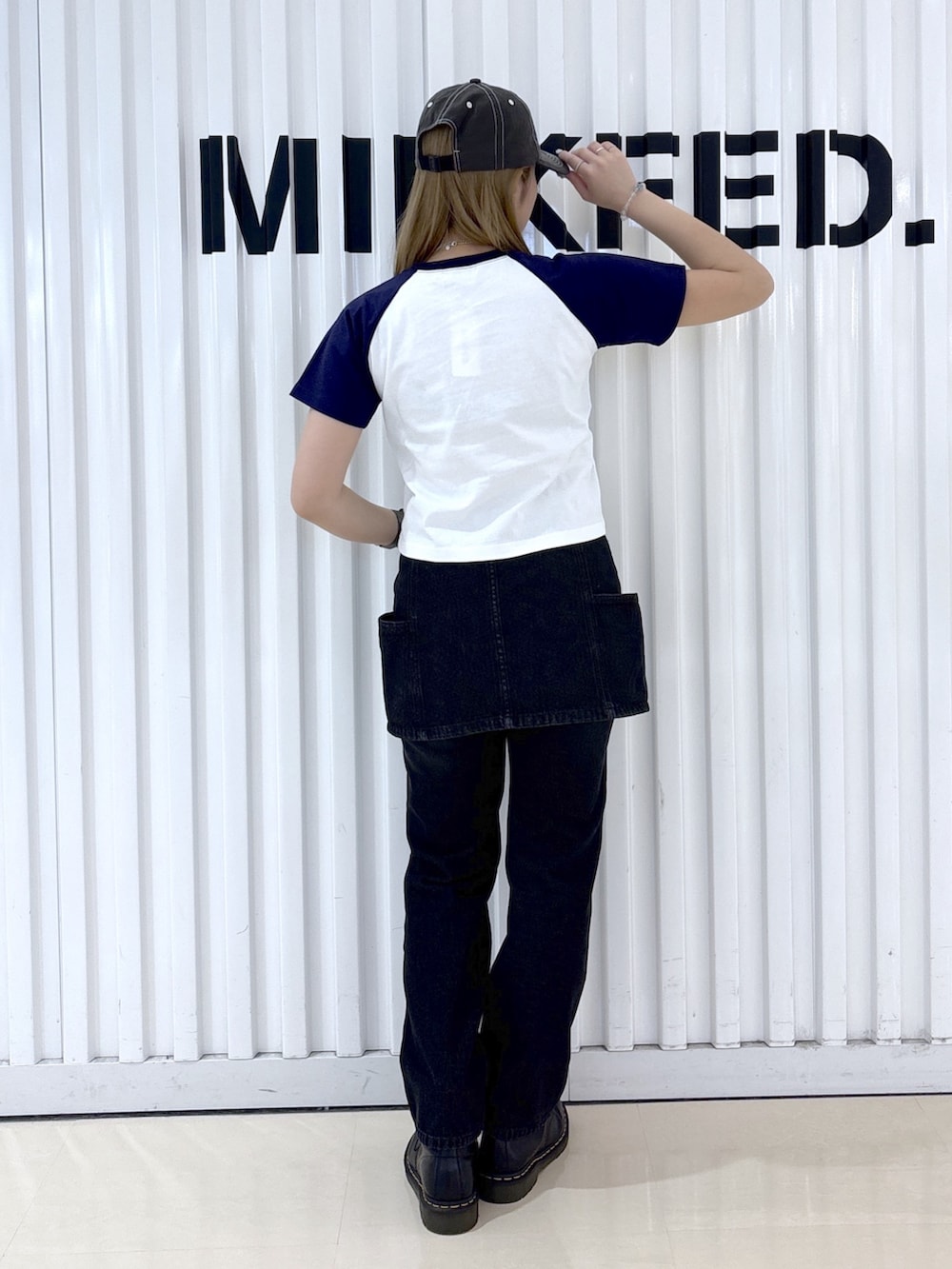 ブラック系のデニムスカート、ブラック系のデニムパンツ、ホワイト系のTシャツ/カットソーを着用したレディースの夏コーディネートの2枚目の写真