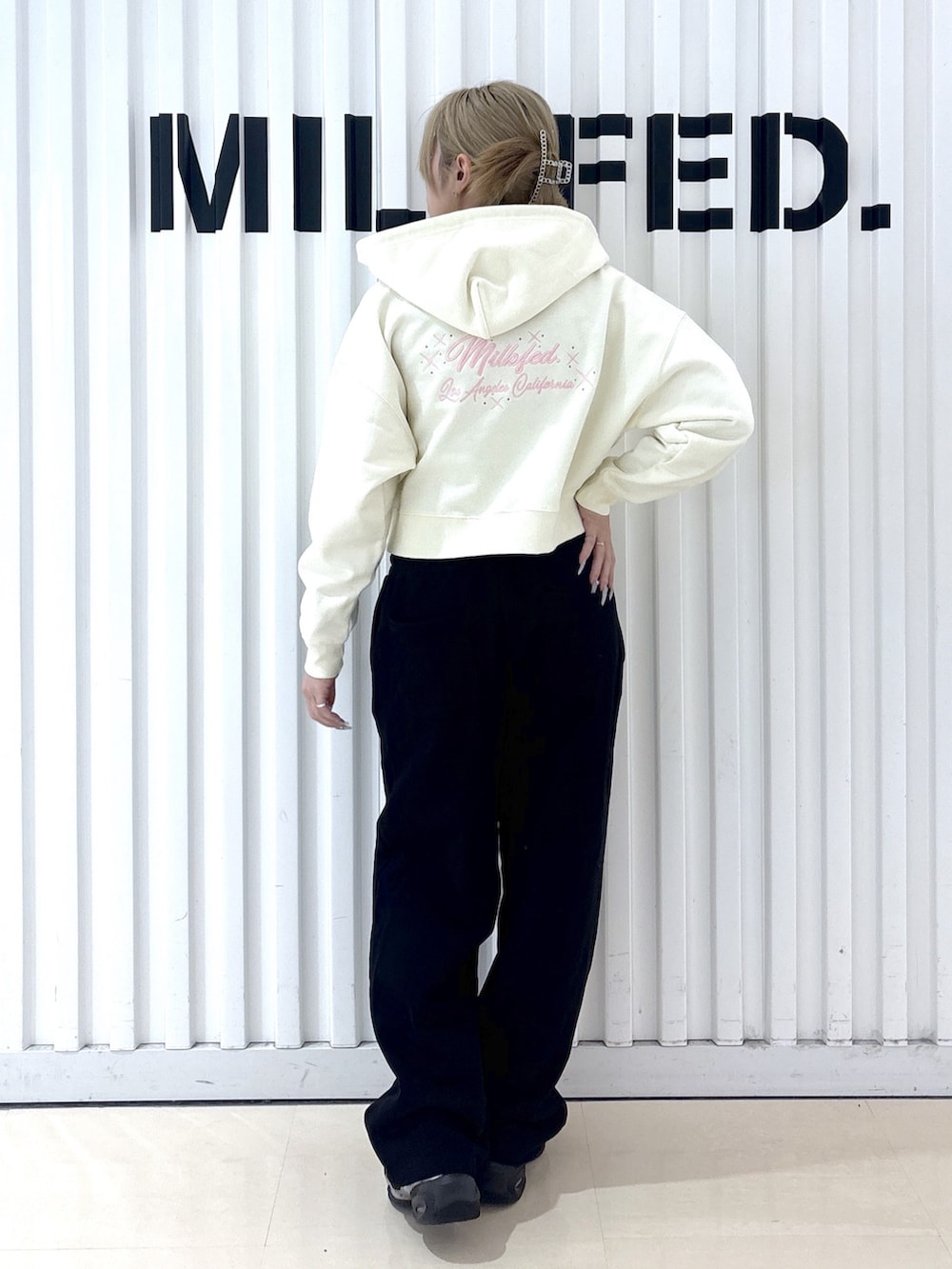 ホワイト系のパーカー、ブラック系のスウェットパンツを着用したレディースの春コーディネートの2枚目の写真