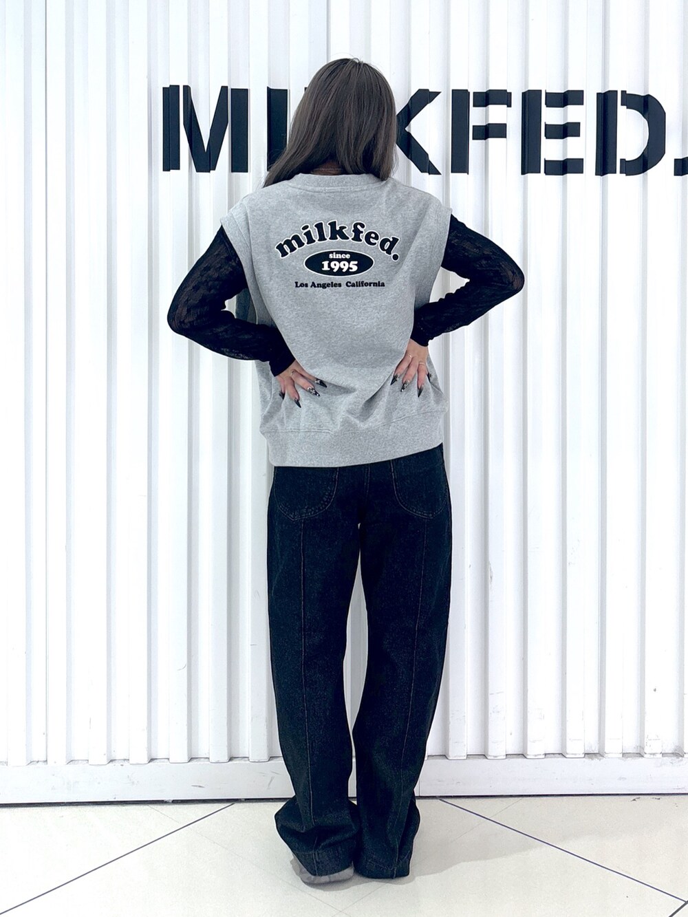 ブラック系のデニムパンツ、グレー系のベスト、ブラック系のTシャツ/カットソーを着用したレディースの秋コーディネートの2枚目の写真