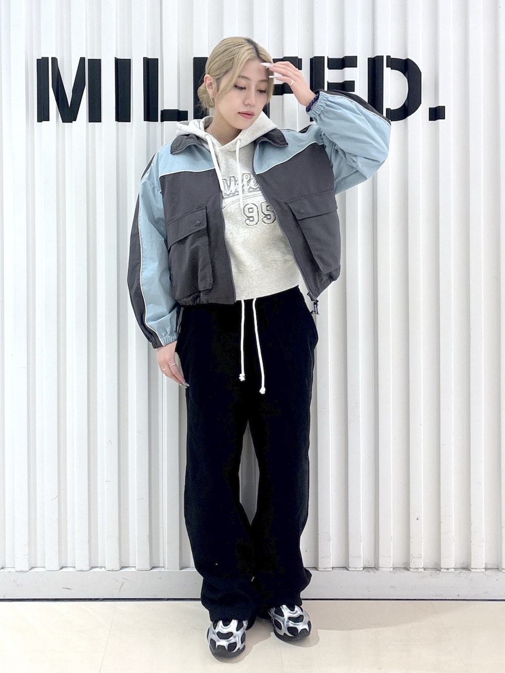 グレー系のナイロンジャケット、ベージュ系のパーカー、ブラック系のスウェットパンツを着用したレディースの春コーディネートの8枚目の写真