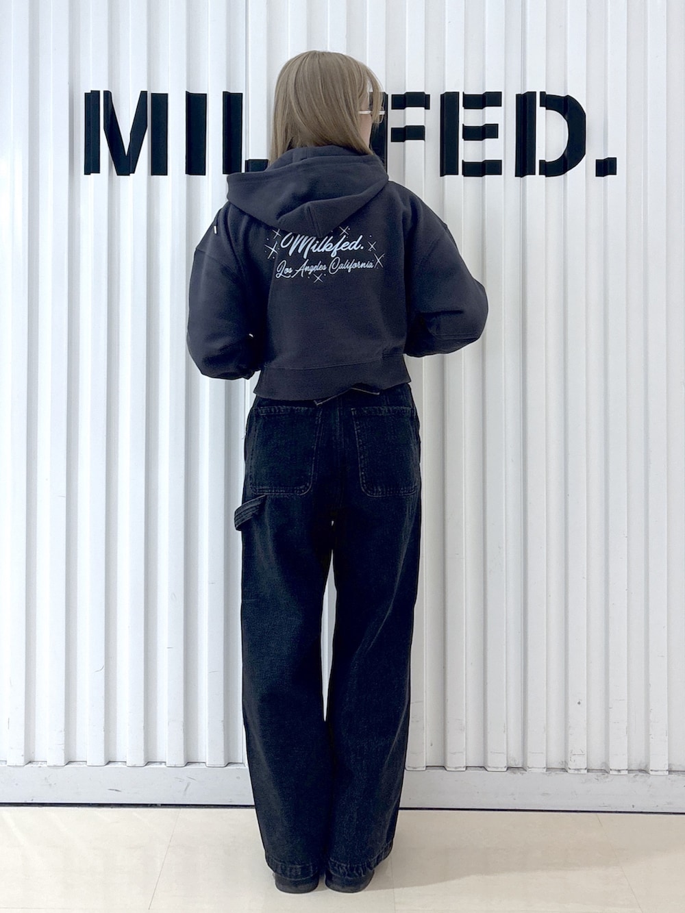 グレー系のパーカー、ブラック系のデニムパンツ、ブラック系のショルダーバッグを着用したレディースの冬コーディネートの4枚目の写真