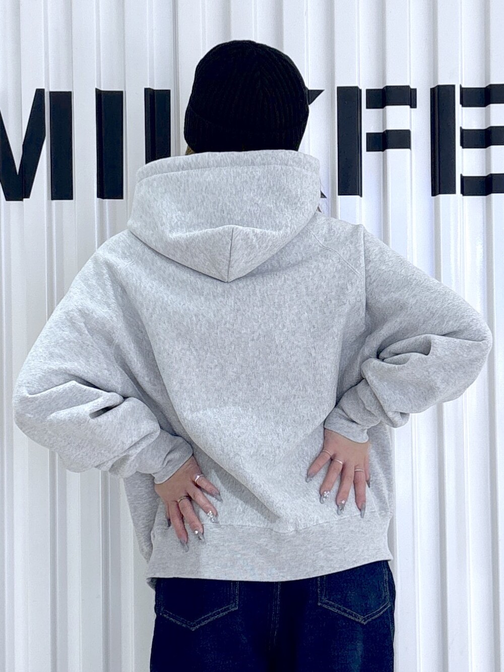 グレー系のパーカー、ブルー系のデニムパンツ、ブラック系のニットキャップ/ビーニーを着用したレディースの冬コーディネートの4枚目の写真