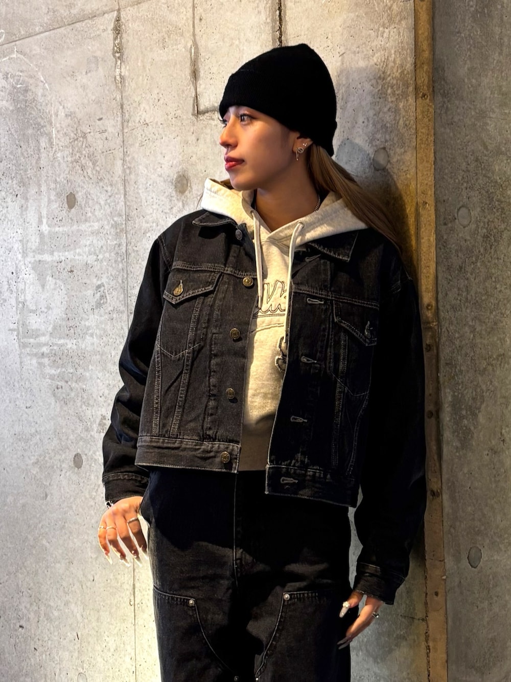 ベージュ系のパーカー、ブラック系のデニムパンツ、ブラック系のデニムジャケットを着用したレディースの春コーディネートの3枚目の写真